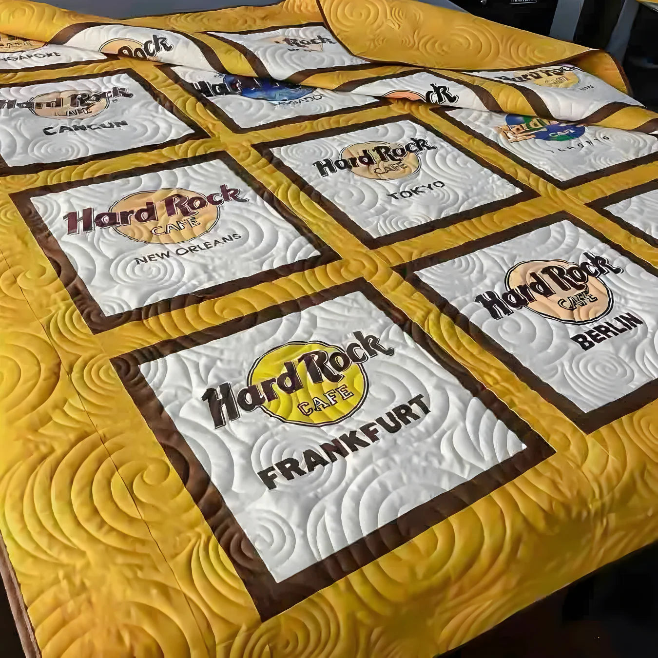 Quilt with Hard Rock Cafe logos and names on a yellow background